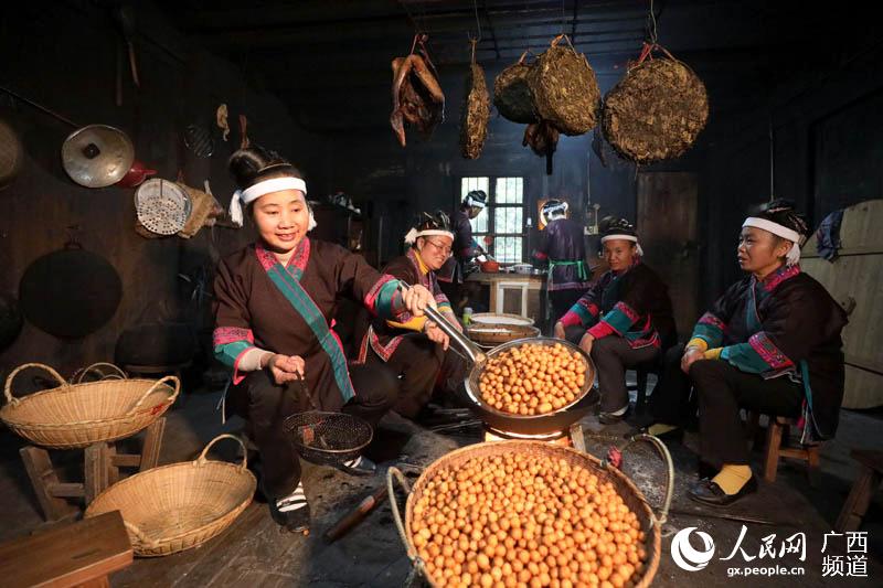 一名妇女在将炸好的油果倒入篮中。龚普康摄