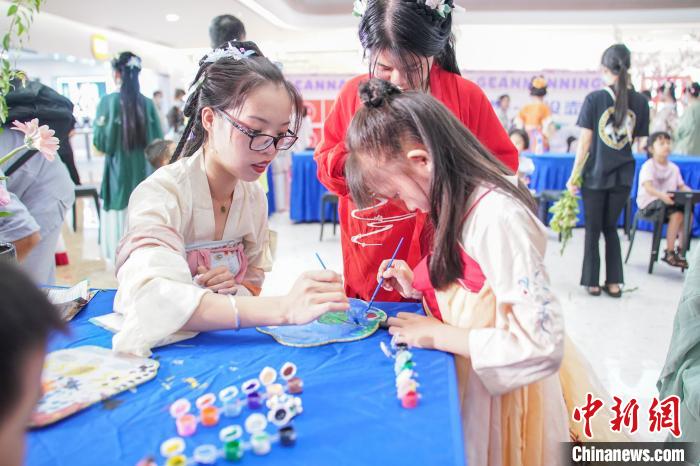 图为广西南宁汉服爱好者身着传统服饰学习画团扇。 陈冠言 摄 图为广西南宁汉服爱好者身着传统服饰学习画团扇。 陈冠言 摄