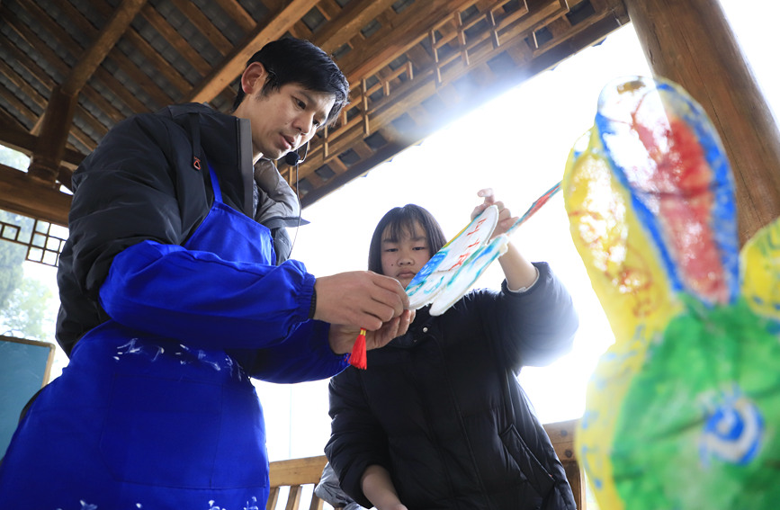 桂林市非物质文化遗产“两江龙灯”传承人梁家庆正在教小朋友制作龙灯。阳海翔摄