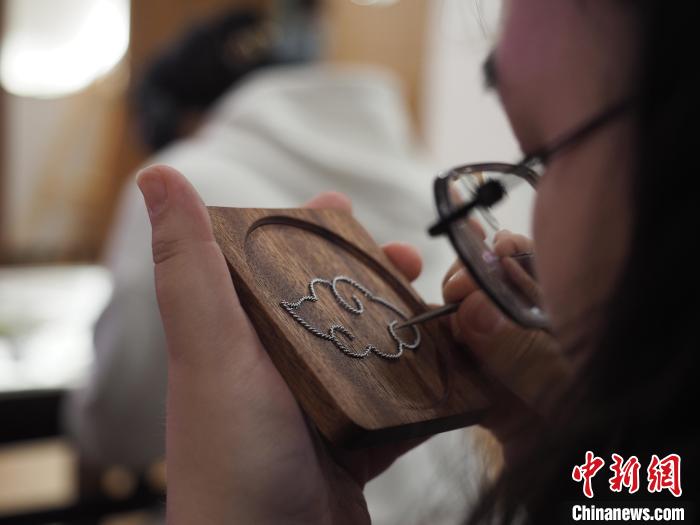 图为一名留学生在聚精会神地制作苗族银饰掐丝画杯垫。 李娇阳 摄 图为一名留学生在聚精会神地制作苗族银饰掐丝画杯垫。 李娇阳 摄
