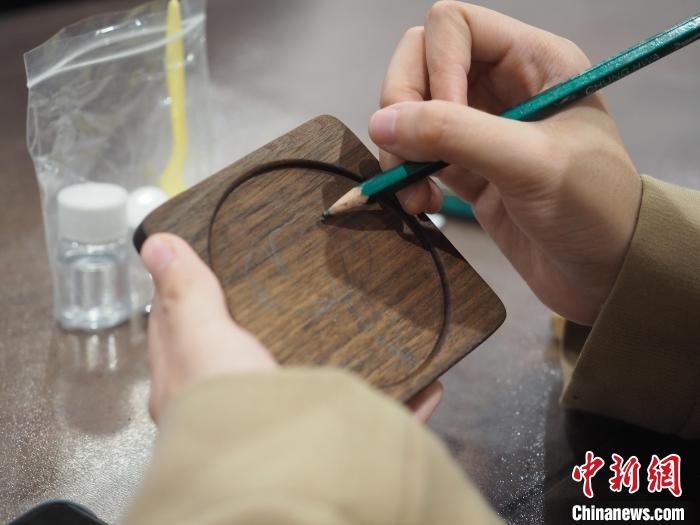 图为一名留学生在杯垫上绘制图案。 李娇阳 摄 图为一名留学生在杯垫上绘制图案。 李娇阳 摄