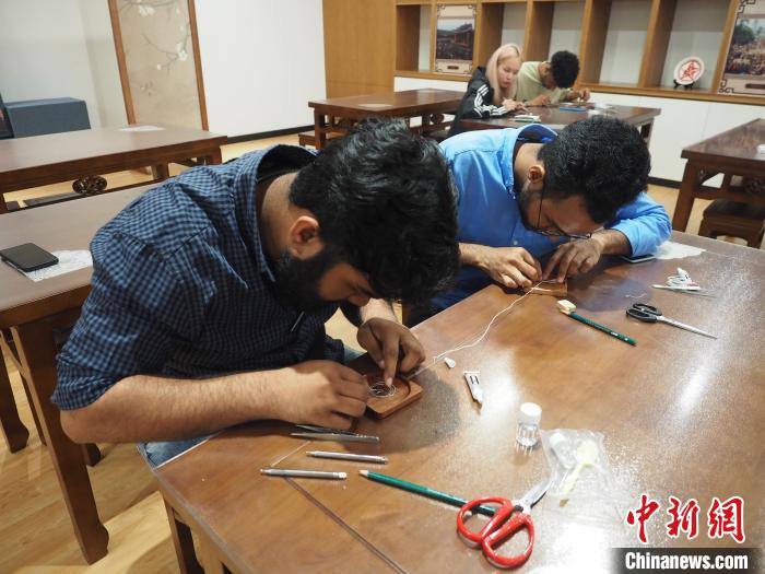 图为留学生们在制作苗族银饰掐丝画杯垫。 李娇阳 摄 图为留学生们在制作苗族银饰掐丝画杯垫。 李娇阳 摄