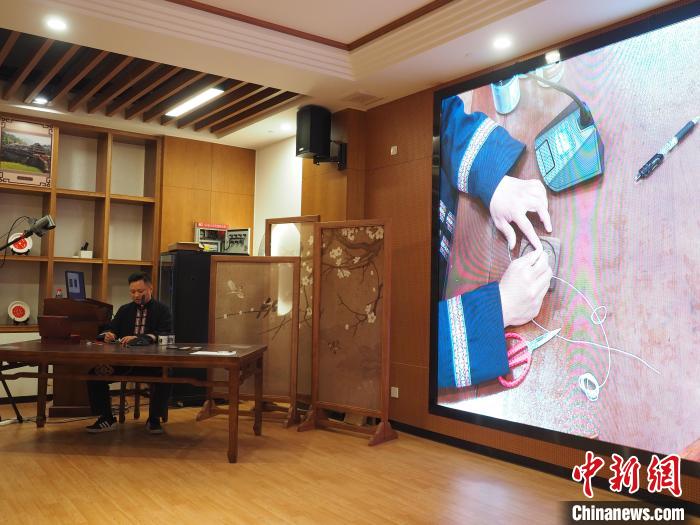 图为工作人员在展示苗族银饰掐丝画杯垫的制作方法。 李娇阳 摄 图为工作人员在展示苗族银饰掐丝画杯垫的制作方法。 李娇阳 摄