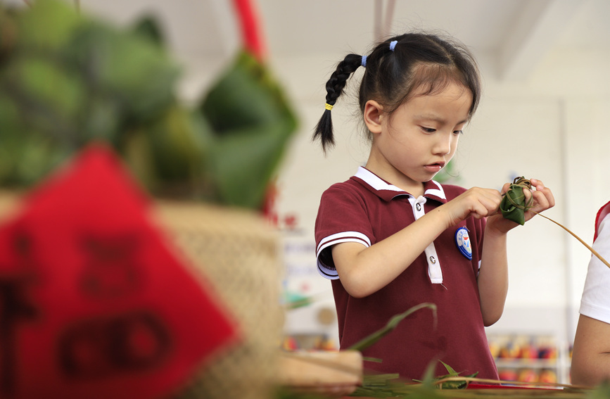 小朋友正在学着包粽子。
