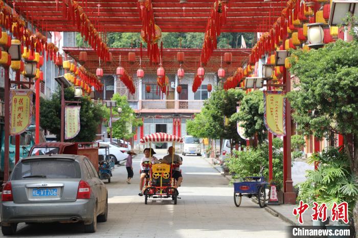 图为在古色古香的街道两边都是各类餐饮店与民宿，路上还有游客体验共享助力车。文嘉仁 摄