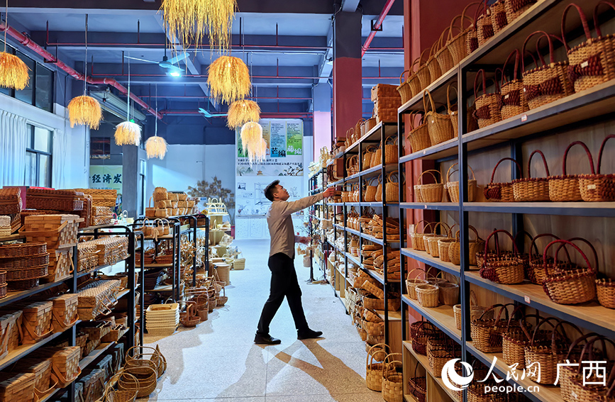 莫思明查看企业生产的非遗工艺品。人民网 付华周摄